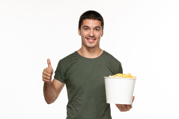 Front view young male in green t-shirt holding basket with potato cips on the white background lonely enjoyment film cinema