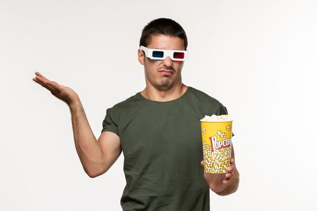 Front view young male in green t-shirt holding popcorn in d sunglasses watching movie on white wall film lonely cinema movies