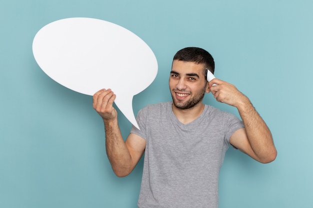 Free photo front view young male in grey t-shirt holding electric razor with white sign on iced blue