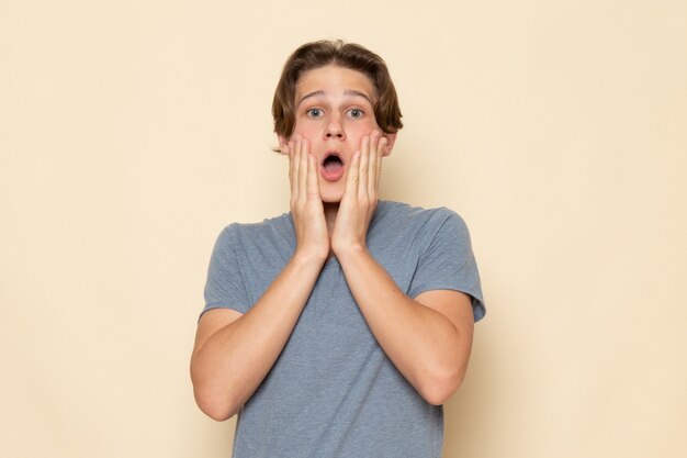 A front view young male in grey t-shirt posing with surprised expression