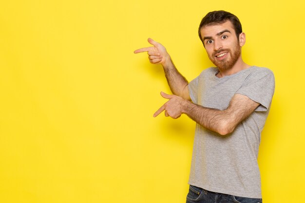 A front view young male in grey t-shirt smiling and posing on the yellow wall man color model emotion clothes