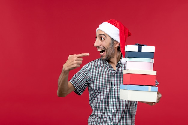 Free photo front view young male happily holding presents on red background