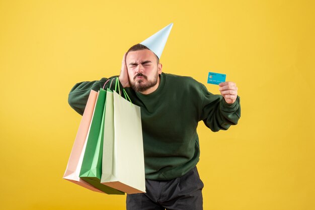 Free Photo front view young male holding bank card and shopping packages on the yellow background