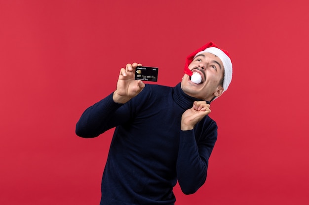 Free Photo front view young male holding black bank card on red background