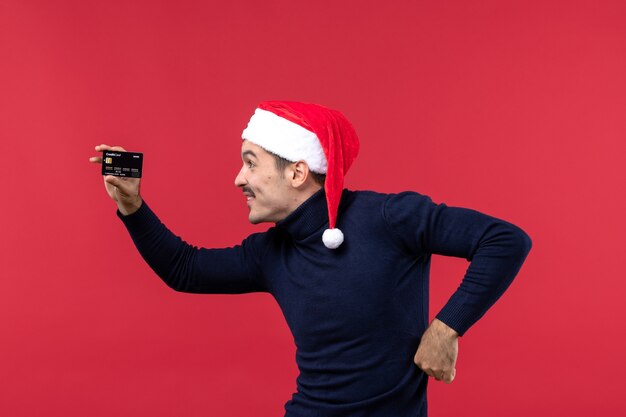 Free photo front view young male holding black bank card on red background