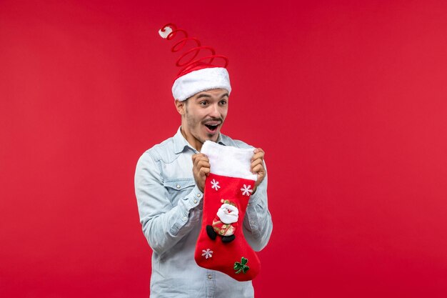 Front view young male holding christmas sock on red desk christmas holiday