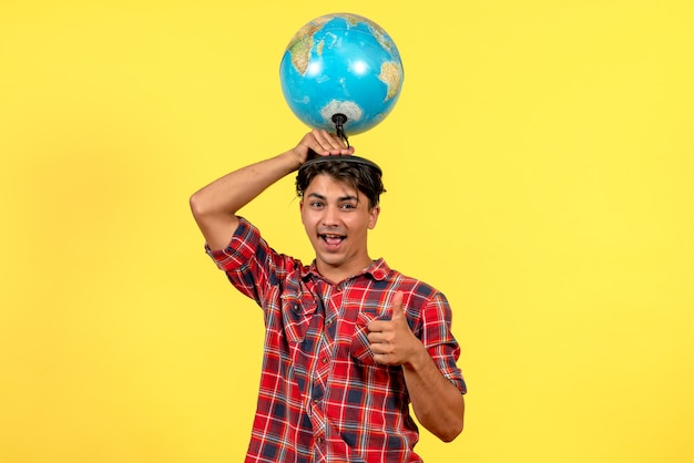 Front view young male holding earth globe on a yellow background male model color