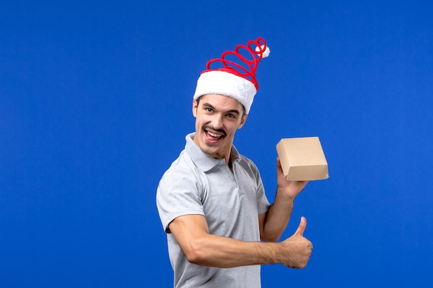 Front view young male holding food package on light-blue wall food male service job