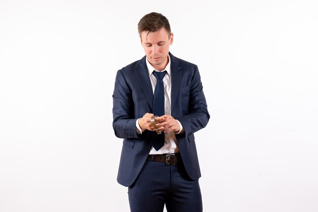 Front view young male holding his watches in classic suit on white background emotion human costume fashion model male