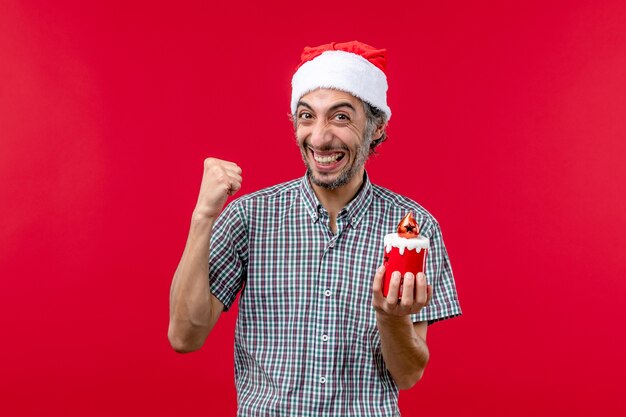 Front view of young male holding little toy on red