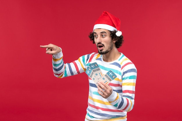 Free Photo front view young male holding plane tickets on red wall red holiday plane new year