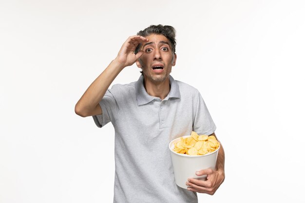 Front view young male holding potato chips on white surface