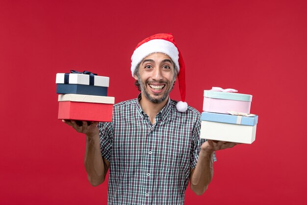 Free Photo front view young male holding presents on red background