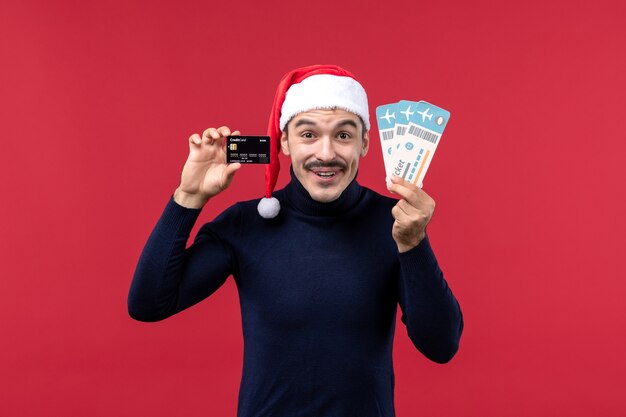 Front view young male holding tickets bank card on red background