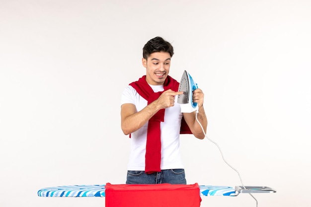 Front view young male behind ironing board holding iron on white