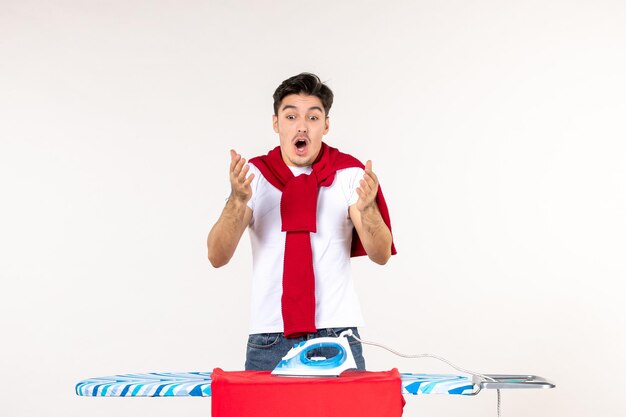 Front view young male ironing towel on white surface