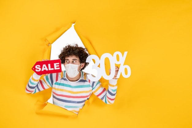 Free photo front view young male in mask holding on a yellow pandemic color shopping red health covid photo virus sale