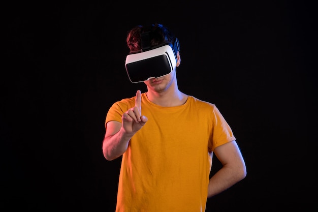 Front view of young male playing virtual reality on dark wall