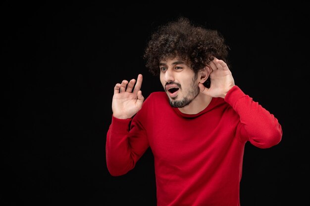 Front view of young male in red shirt on black wall