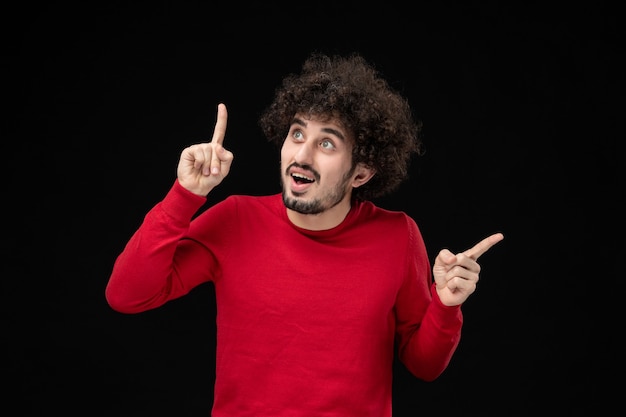 Front view of young male in red shirt on black wall