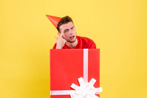 Front view young male in red shirt sitting inside present box