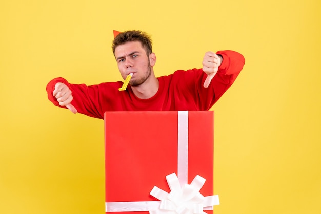 Front view young male in red shirt sitting inside present box