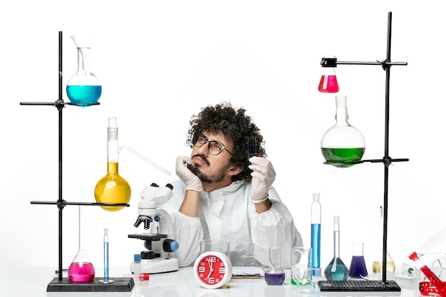 Free Photo front view young male scientist in special suit holding samples and thinking on white wall