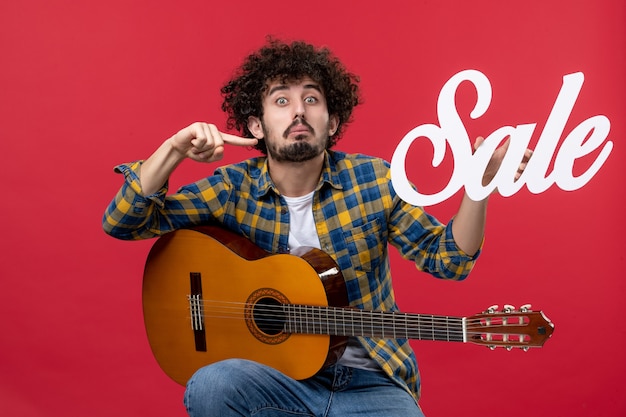 Free Photo front view young male sitting with guitar on a red wall music sale play concert applause live musician color