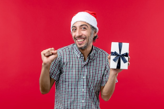 Front view of young male smiling with little present on red