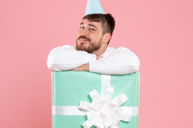 Free photo front view young male standing inside present box on pink xmas photos color emotion pajama party