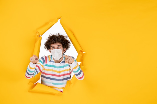 Front view young male in sterile mask on yellow color covid- human pandemic virus photo