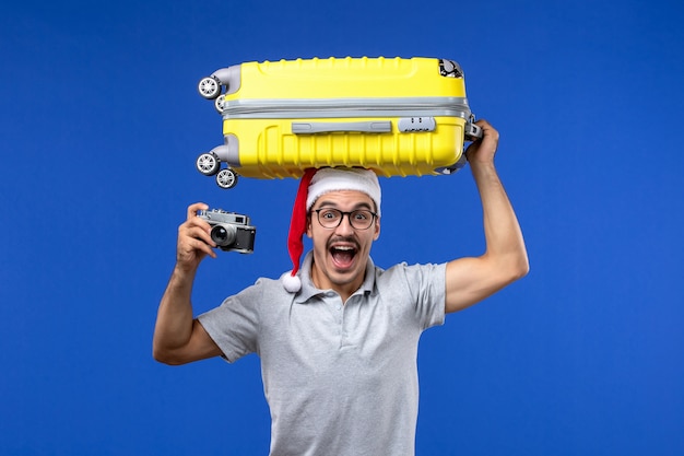 Free Photo front view young male taking photo and holding bag on blue wall flights vacation planes