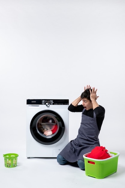 Free photo front view of young male waiting until the end of clothes washing on a white wall