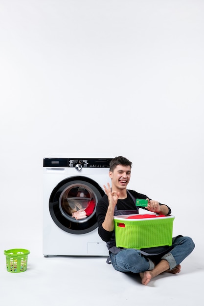 Free photo front view of young male waiting until the end of clothes washing on white wall