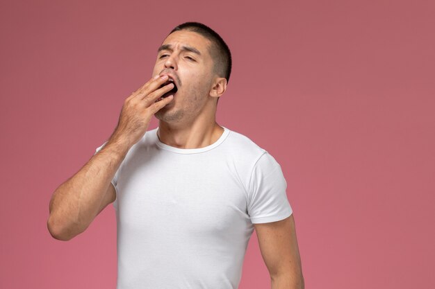 Front view young male in white shirt yawning on pink background 