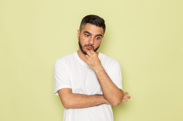 A front view young male in white t-shirt deeply thinking