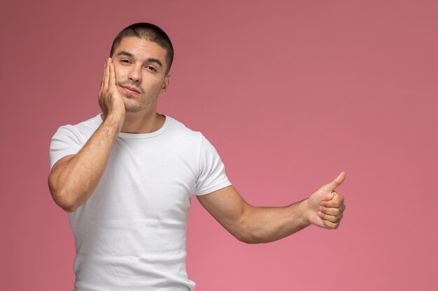 Front view young male in white t-shirt posing having toothache on pink background  