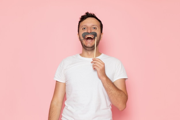 A front view young male in white t-shirt posing and holding mustache