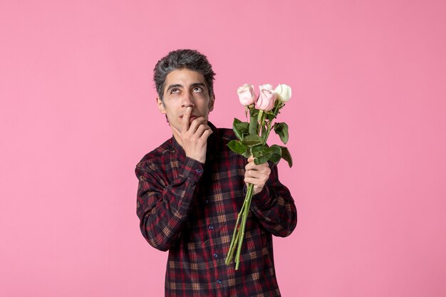 Front view young male with beautiful pink roses on pink wall