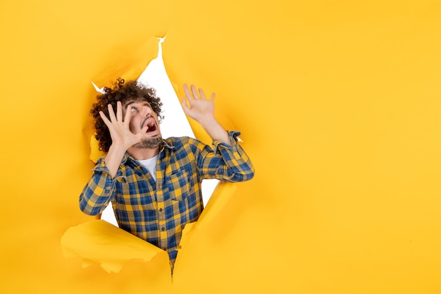 Front view young male with curly hair with scared face on yellow ripped background