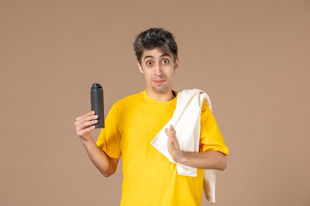 front view young male with foam and towel preparing to shave his face on pink background