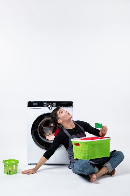 Free photo front view of young male with green basket full of clothes holding bank card on a white wall