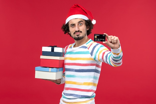 Free photo front view young male with holiday presents and bank card on red desk new year money red