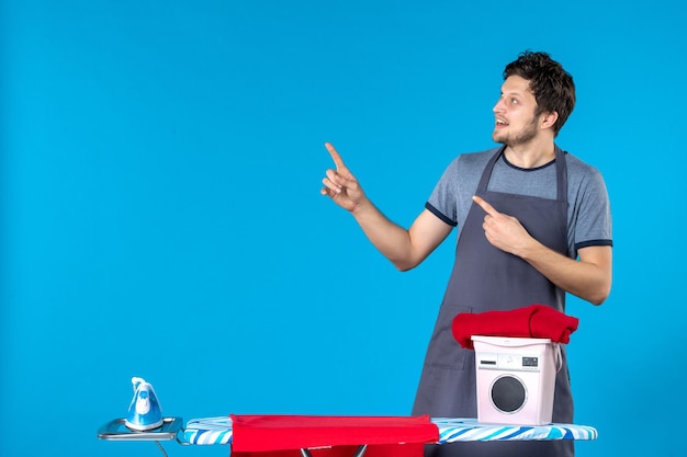 Free photo front view young male with ironing board on a blue background iron color cleaning man washing machine laundry housework