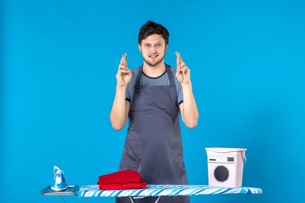 Front view young male with ironing board on blue surface