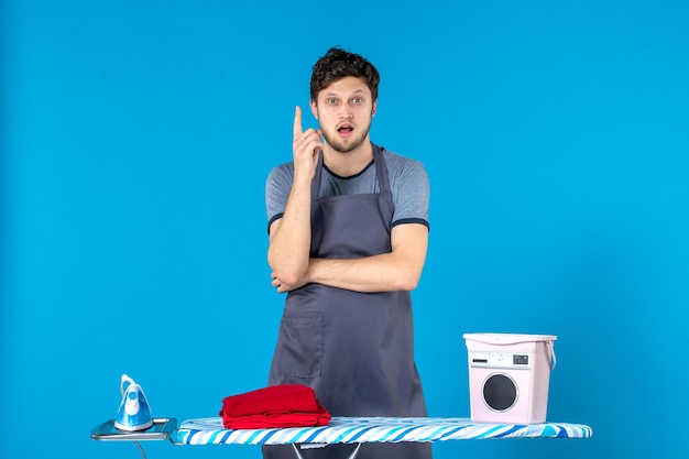 Free photo front view young male with ironing board on the blue surface