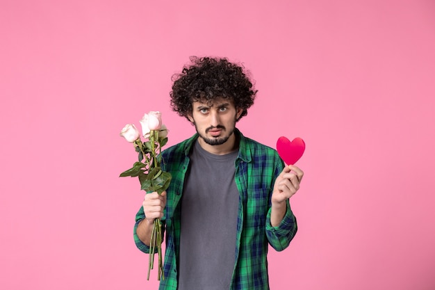 Free photo front view young male with pink roses and heart sticker on pink