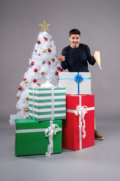 Front view young male with presents and envelop on a grey