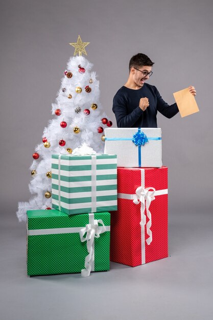 Front view young male with presents on a grey