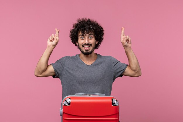 Front view young male with red bag crossing hsi fingers on pink space